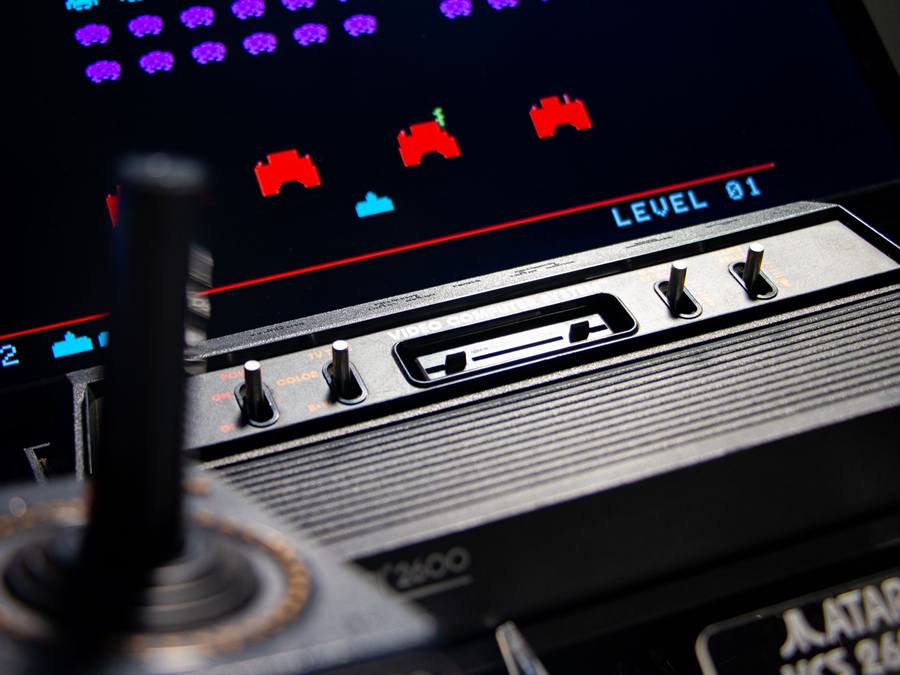 Console Atari 2600 et son joystick devant un écran Space Invaders